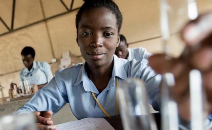 Adolescente realiza un experimento durante una clase de química en la Escuela secundaria de Zambia. Foto UNICEF
