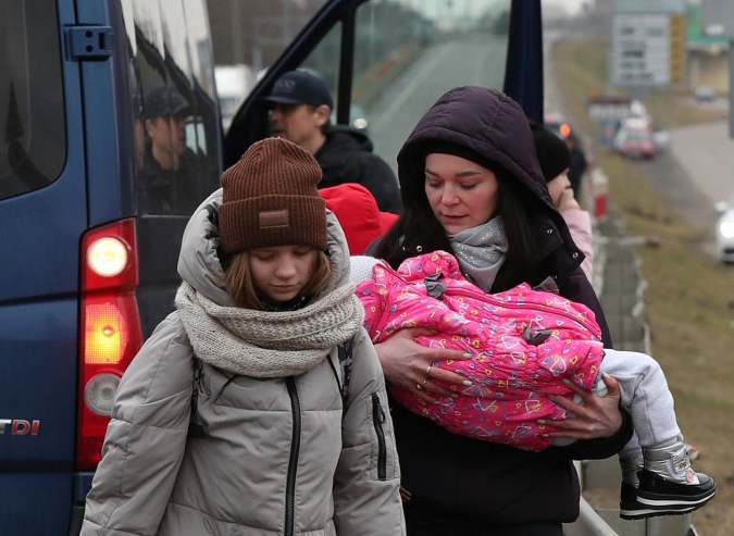 Una mujer sostiene a un niño antes de cruzar la frontera de Ucrania con Polonia por el paso de Dorohusk. Foto: El País.